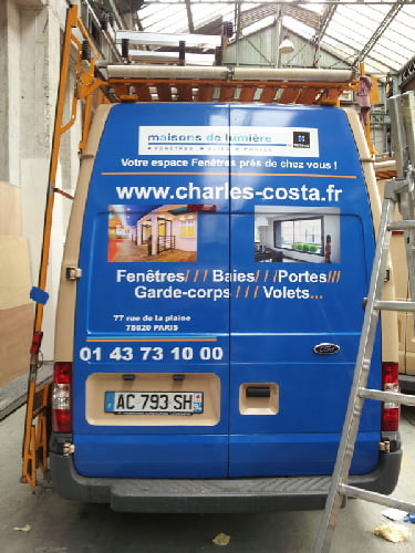 une camionnette bleue avec une publicité blanche et bleue pour le semi covering de charles costa
